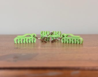 May include: Three lime green plastic keychains with a comb-like design and silver key rings.