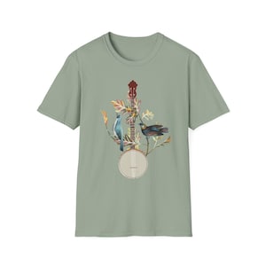 May include: A sage green t-shirt with a banjo, two birds, and floral accents printed on the front.