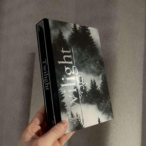 Peut inclure: Un livre noir et argent avec le titre "Twilight" sur le dos et une sc&egrave;ne de for&ecirc;t brumeuse sur la couverture.