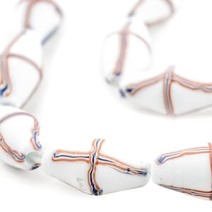 Pode incluir: Um fio de contas de vidro branco com listras marrons e azuis. As contas são de forma oval e têm um padrão de grade.