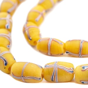 Puede incluir: Una hebra de cuentas de vidrio amarillo con rayas azules y blancas. Las cuentas son de forma ovalada y tienen un acabado brillante.