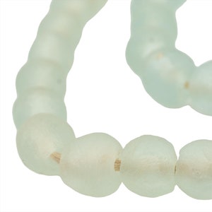 Puede incluir: Una hebra de cuentas de vidrio esmerilado en color azul claro. Las cuentas son de forma ovalada y están enhebradas en un cordón delgado.