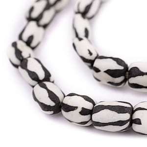 May include: A strand of white and black striped beads. The beads are oval shaped and have a textured surface.