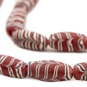 May include: A strand of red and white striped glass beads. The beads are oval shaped and have a swirling pattern.