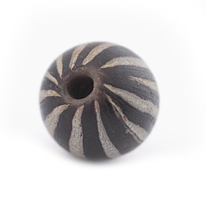 Peut inclure: Une perle sphérique gris foncé avec un motif en spirale de rayures gris clair. La perle a un trou traversant le centre et est posée sur un fond blanc. Idéale pour la fabrication de bijoux.