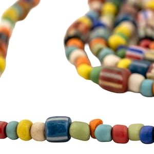 Pode incluir: Um colar de contas coloridas com uma variedade de formas e tamanhos. As contas são em tons de vermelho, azul, amarelo, verde e laranja. Algumas contas têm listras ou padrões. O colar está em um fundo branco.