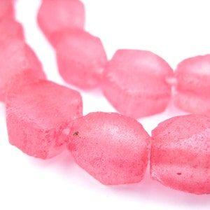 May include: A strand of pink glass beads with a faceted, irregular shape. The beads are translucent and have a slightly frosted finish.