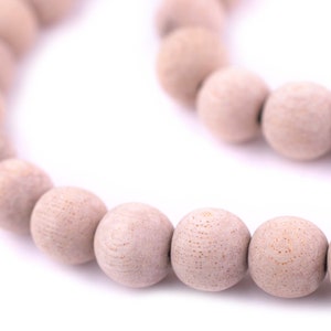 Könnte beinhalten: Eine Schnur aus hellbraunen Holzperlen, die zu einem Kreis geformt sind. Die Perlen sind glatt und haben eine natürliche Holzmaserung.