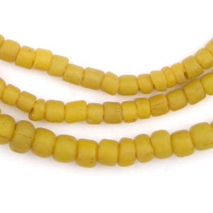 May include: A strand of yellow glass beads. The beads are small and round, and they have a slightly matte finish.