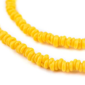 May include: A close-up of a yellow beaded necklace. The beads are small and round, and they are strung together in a long strand.