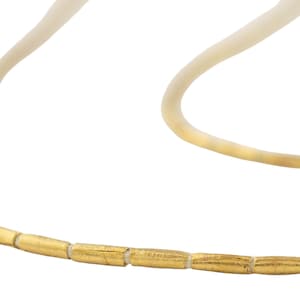 Puede incluir: Un collar de oro con una cadena hecha de pequeñas cuentas cilíndricas.