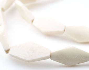 May include: Off-white necklace featuring geometric, diamond-shaped beads. The beads are strung together, creating a continuous loop. The necklace is made of a solid, opaque material, and the beads have a slightly textured surface.