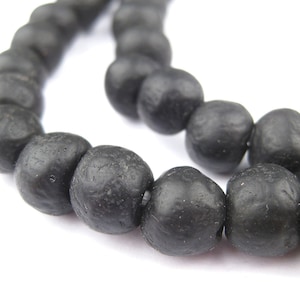 May include: A strand of black beads, each bead is round and has a textured surface.