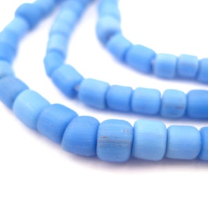 May include: Close-up of strands of light blue beads. The beads are cylindrical with rounded edges and vary slightly in shade, creating a gradient effect. The beads are strung together, suggesting jewelry or craft supplies.