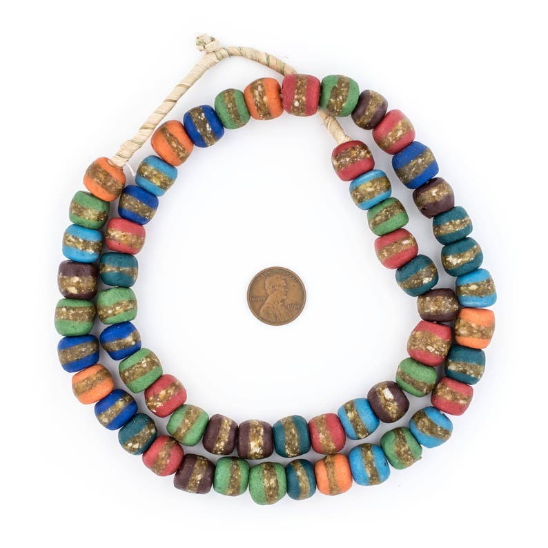 Puede incluir: Una hebra de cuentas de vidrio de colores rayadas con acentos dorados. Las cuentas est&aacute;n enhebradas en un cord&oacute;n de fibra natural y tienen aproximadamente 2,5 cm de di&aacute;metro.