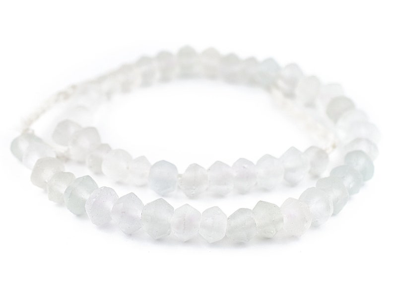 May include: A strand of white glass beads with a faceted, irregular shape. The beads are strung on a thin, white cord.