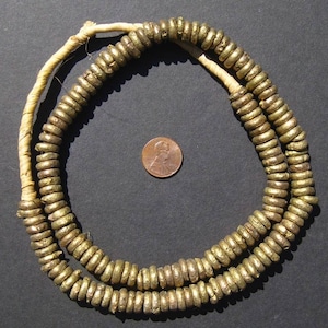 May include: A gold necklace made of small, round beads. The beads are strung on a white cord. The necklace is approximately 50 cm long.