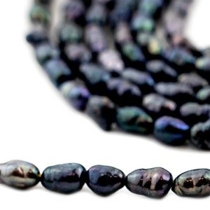 Peut inclure: Un collier de perles d'eau douce noires avec un éclat iridescent. Les perles sont de forme ovale et ont une finition lisse et polie.