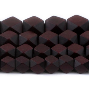 May include: A close-up of a strand of dark red faceted beads. The beads are made of glass and have a matte finish.