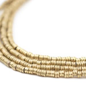 Może przedstawiać: Zbliżenie na sznur złotych koralików. Koraliki są małe i okrągłe, a nawleczone są na długą, ciągłą nić.