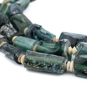 Könnte beinhalten: Nahaufnahme einer Halskette aus dunkelgrünen und hellgrünen Glasperlen. Die Perlen sind zylindrisch und haben eine raue, strukturierte Oberfläche. Einige der Perlen sind durch kleine, weiße Perlen getrennt.