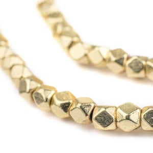 May include: A strand of gold-toned metal beads, each bead is faceted and has a geometric shape.