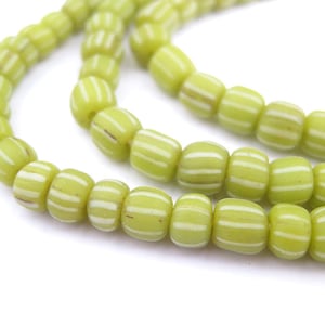 May include: A strand of green glass beads with white stripes. The beads are round and have a slightly irregular shape.