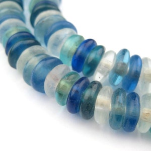 May include: Close-up of two strands of blue and clear glass beads. The beads vary in shades of blue, from deep navy to light turquoise, and are interspersed with clear beads. The beads are round and have a slightly irregular shape, suggesting they are handmade.