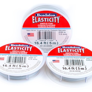 Puede incluir: Tres carretes de cord&oacute;n el&aacute;stico Beadalon Elasticity en plata. Cada carrete est&aacute; etiquetado con el texto "Beadalon Elasticity Stretch Cord Cordon Elastique Cordon Elastico" y el tama&ntilde;o del cord&oacute;n en pulgadas y mil&iacute;metros. Los carretes est&aacute;n etiquetados con los tama&ntilde;os 0,039 pulg (1,0 mm), 0,020 pulg (0,5 mm) y 0,032 pulg (0,8 mm).