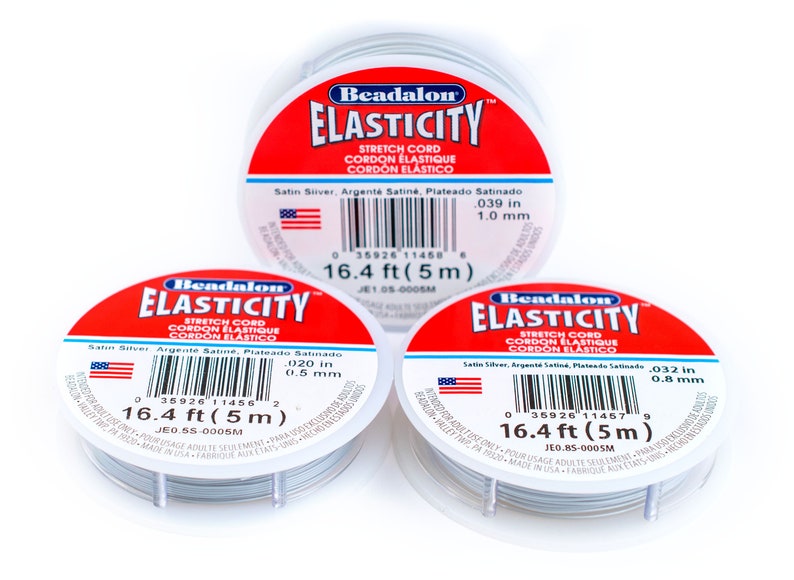 Puede incluir: Tres carretes de cord&oacute;n el&aacute;stico Beadalon Elasticity en plata. Cada carrete est&aacute; etiquetado con el texto "Beadalon Elasticity Stretch Cord Cordon Elastique Cordon Elastico" y el tama&ntilde;o del cord&oacute;n en pulgadas y mil&iacute;metros. Los carretes est&aacute;n etiquetados con los tama&ntilde;os 0,039 pulg (1,0 mm), 0,020 pulg (0,5 mm) y 0,032 pulg (0,8 mm).