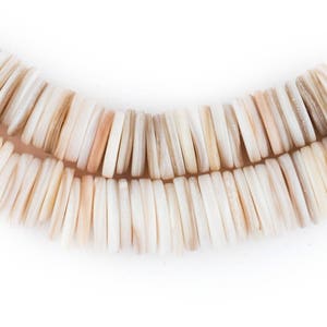 May include: Close-up of a necklace made of rectangular, off-white beads with subtle variations in color, including hints of beige and peach. The beads are arranged in two parallel strands, creating a curved shape against a white background.