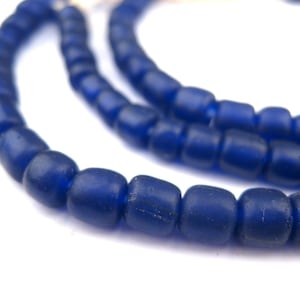 Pode incluir: Um fio de contas de vidro azul escuro. As contas são redondas e têm um acabamento fosco.