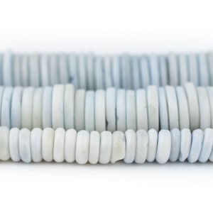 May include: A close-up of a strand of light blue and white round beads. The beads are arranged in rows, creating a pattern of alternating colors.
