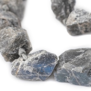 Puede incluir: Una hebra de cuentas de piedra preciosa de labradorita gris y azul enhebradas en un cordón plateado.