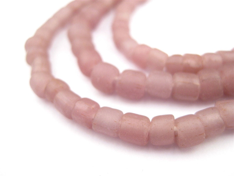 May include: A strand of pale pink glass beads, each bead is a slightly irregular square shape.