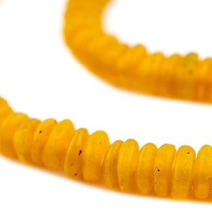 Könnte beinhalten: Eine Strähne gelber Glasperlen, jede Perle ist eine flache Scheibe mit einer leicht erhabenen Mitte.