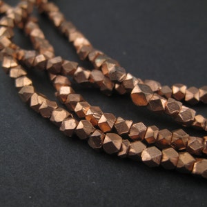 May include: A strand of copper-colored faceted beads. The beads are small and have a rough, hammered texture.