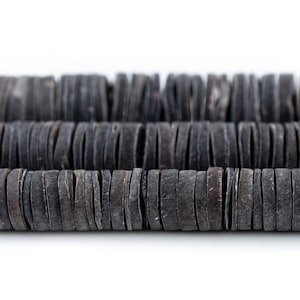 May include: A strand of black, round, wooden beads. The beads are stacked on top of each other, creating a layered effect.