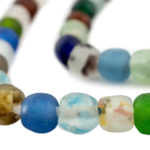 May include: A strand of colorful, rounded beads in various shades of blue, green, brown, and white. The beads are strung together, creating a necklace or bracelet. The beads have a slightly irregular shape.