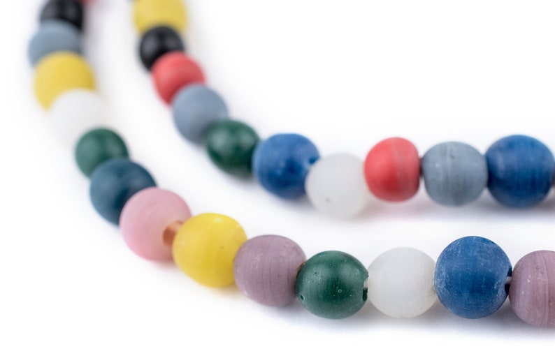 Puede incluir: Primer plano de dos hilos de cuentas redondas de colores. Las cuentas son de varios colores, incluyendo blanco, amarillo, rosa, verde, azul, rojo y gris. Las cuentas est&aacute;n ensartadas, creando un collar o pulsera.