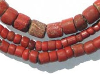 May include: Close-up of three strands of red beads. The top strand features cylindrical beads, the middle strand has a mix of cylindrical and square beads, and the bottom strand has small, rounded beads. The beads are strung together, creating a necklace.