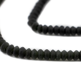 May include: A strand of black faceted glass beads. The beads are small and round, and they have a matte finish.