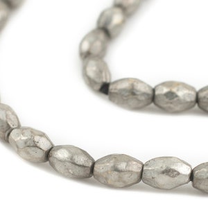 May include: A strand of silver-toned metal beads with a hammered finish. The beads are oval-shaped and have a slightly irregular texture.