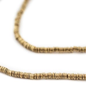 Puede incluir: Un collar de oro hecho de pequeñas cuentas redondas. Las cuentas están dispuestas en una sola hebra y están espaciadas uniformemente.