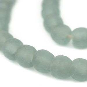 May include: A strand of light blue glass beads. The beads are round and have a frosted finish.