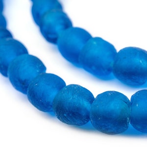 May include: A strand of bright blue glass beads, each bead is slightly oval shaped and has a frosted finish.