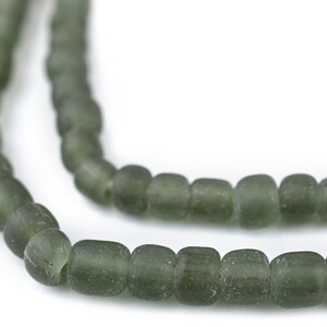 May include: Close-up of a strand of olive green beads. The beads are rectangular with rounded edges and appear to be made of glass. The beads are strung together, creating a necklace or bracelet.