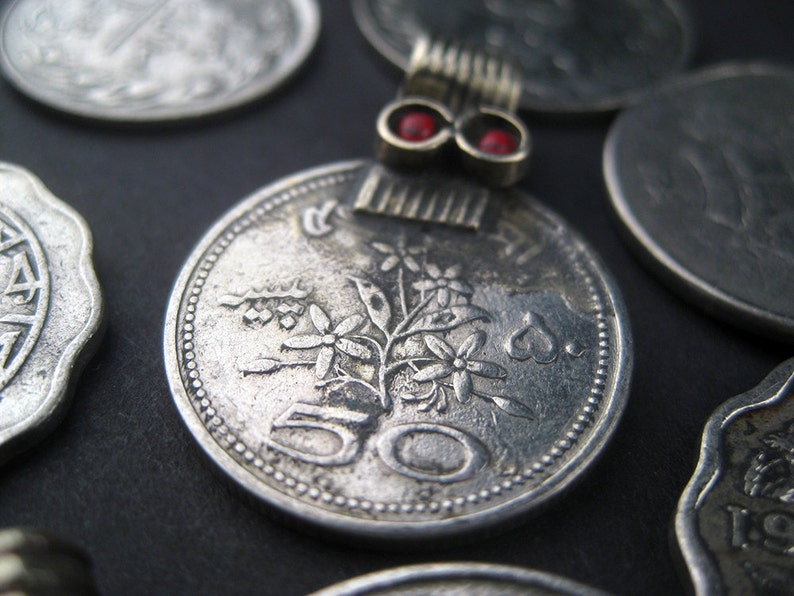 May include: A silver coin with a floral design and the number 50 on it. The coin is surrounded by other coins.