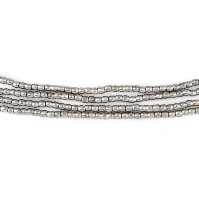 May include: A strand of silver beads, arranged in five rows, with a smooth, slightly textured finish.