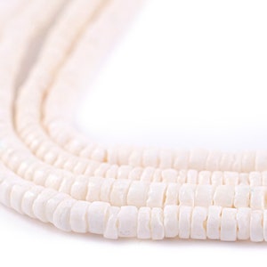 Könnte beinhalten: Eine Nahaufnahme einer weißen Muschelperlenkette. Die Perlen sind rund und haben eine glatte, polierte Oberfläche.